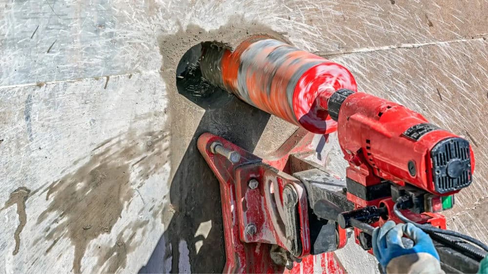 Powerful drill cutting through concrete with a core drill bit, showcasing precision and strength.